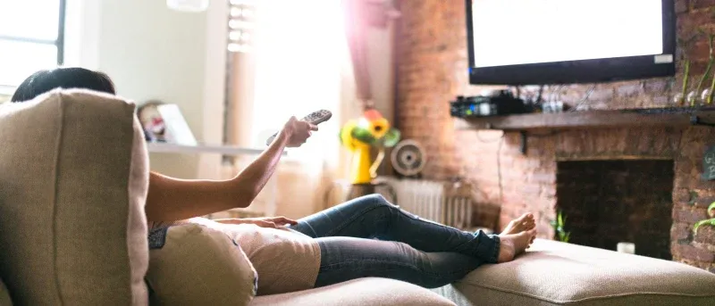 Woman relaxing online on sofa watching tv